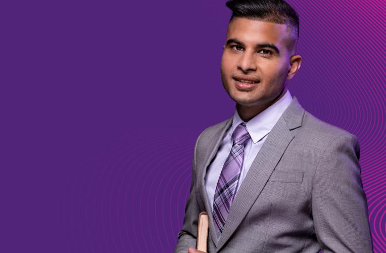 A postgraduate student wearing a suit and tie, smiling.